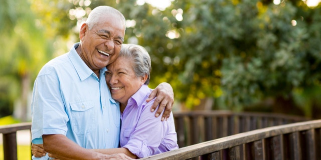 A mexican senior couple laughing together on bridge.