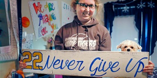 In this Dec. 8, 2014, file photo, Lauren Hill holds a sign made for her, which she keeps in her room in Cincinnati, along with many other messages and gifts of support. (AP Photo/The Enquirer, Carrie Cochran, File)
