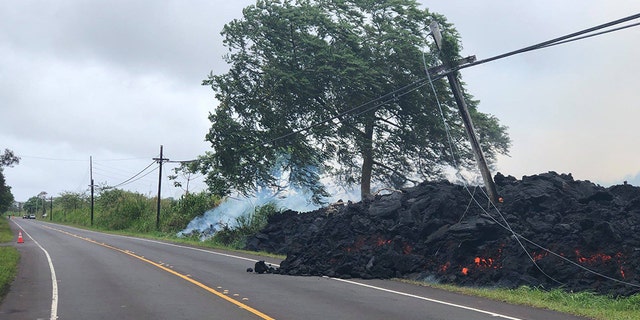 A fast-moving lava flow covers Highway 132 in Hawaii on Tuesday, taking out utility poles and knocking out power in the area.