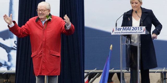 France's far-right National Front political party leader Marine Le Pen (R) watches as her father Jean-Marie Le Pen, party founder and honorary president, reacts on the podium at their traditional May Day tribute to Joan of Arc in Paris, France.