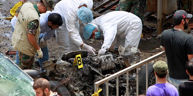 July 9, 2013: Forensic experts inspect the remnants of a car bomb at the scene of a bombing in the Beir el-Abed, a southern suburb of Beirut, Lebanon. A large explosion rocked a stronghold of the Shiite militant Hezbollah group south of the Lebanese capital Tuesday, setting several cars on fire, sending a thick plume of black smoke billowing into the sky and wounding more than a dozen people, security officials said.