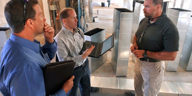 In this Sept. 29, 2015, photo, Scott Abbott, a retired Illinois State Police colonel, speaks with Mark Lewis, left, and Jeff Greer at the new medical marijuana dispensary being built in Collinsville, Ill. Abbott is the director of security and compliance with Health Central, Lewis is the director of finance and human resources for Health Central and Greer is with LRS Network Support. (Steve Nagy/Belleville News-Democrat via AP)