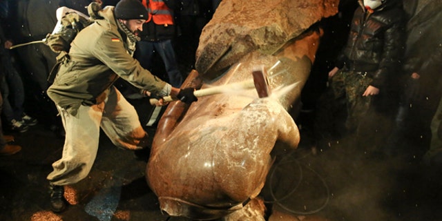 A man holds a sledgehammer as he smashes a statue of Soviet state founder Vladimir Lenin in Kiev.
