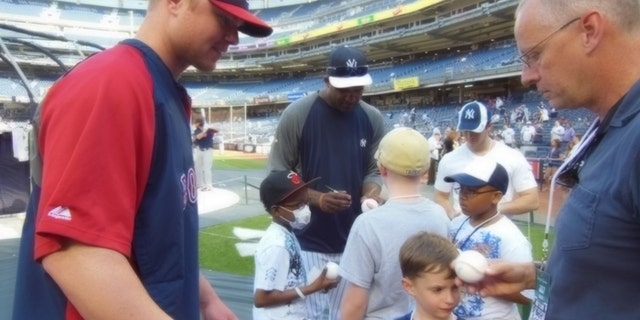Red Sox ace Jon Lester makes time to sign autographs for kids with cancer, as does rival Yankees pitcher CC Sabathia (background).