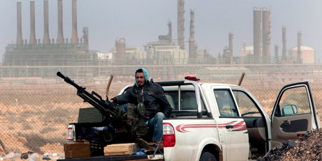 FILE - In this March 5, 2011 file photo, an anti-government rebel sits with an anti-aircraft weapon in front an oil refinery in Ras Lanouf, eastern Libya. The fight for Libyas Ras Lanuf refinery and nearby Sidr depot threatens to spiral into open conflict between rival factions vying for power from east and west. With both sides claiming the facilities as their own but control unclear, decisive days lie ahead. (AP Photo/Hussein Malla, File)