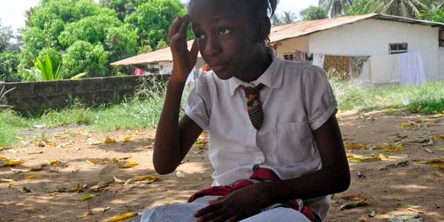 In this photo taken on Friday, May 8, 2015, Mercy Kennedy looks up as she does her homework after school at her home in Monrovia, Liberia. On the day Mercy Kennedy lost her mother to Ebola, it was hard to imagine a time Liberia would be free of one of the worldâs deadliest viruses. It had swept through the 9-year-oldâs neighborhood, killing people house by house. Now seven months later, Liberia on Saturday officially marked the end of the epidemic that claimed more than 4,700 lives here, and Mercy is thriving in the care of a family friend not far from where she used to live. (AP Photo/ Abbas Dulleh)