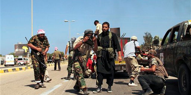 Revolutionary fighters take cover from heavy artillery, rocket and missile counter-attacks launched by Qaddafi loyalists in Sirte, Libya, Saturday, Sept. 24, 2011