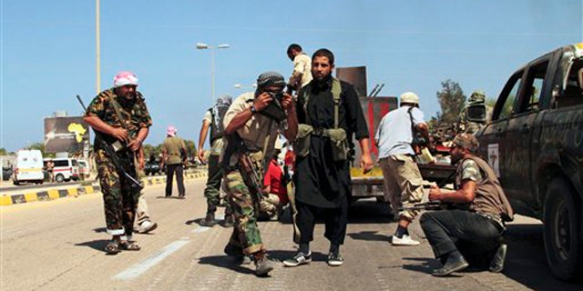Revolutionary fighters take cover from heavy artillery, rocket and missile counter-attacks launched by Qaddafi loyalists in Sirte, Libya, Saturday, Sept. 24, 2011