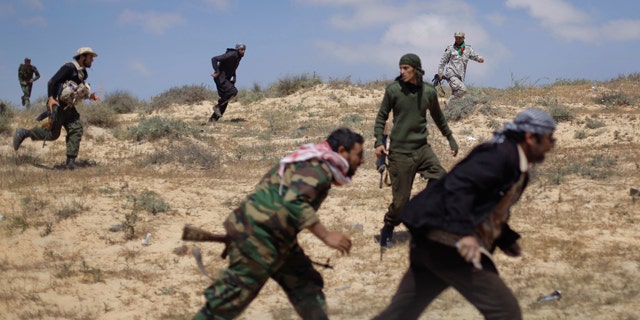 April 4: Rebel fighters run for cover from incoming shelling by pro-Qaddafi forces, near the front line in Brega, Libya. Libyan rebels pushed into the strategic oil town of Brega on Monday but came under fire from Muammar Qaddafi's forces, as a government envoy began a diplomatic push in Europe to discuss an end to the fighting. (AP)