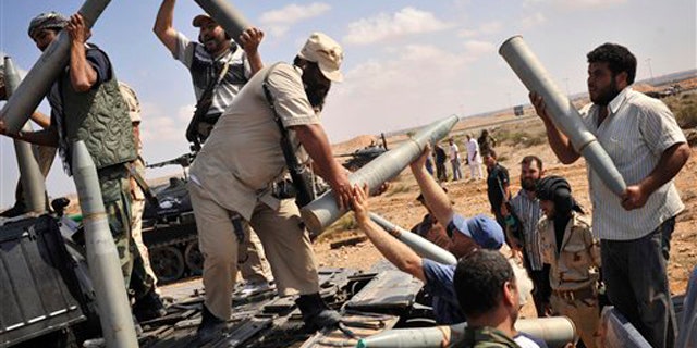 Libyan revolutionary fighters load munitions to be fired during an attack for the city of Sirte, Libya, Wednesday, Oct. 5, 2011.