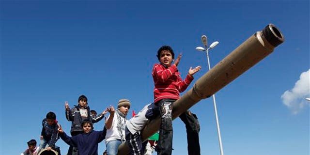 Feb. 28, 2011: Libyan boys sitting on the cannon of a destroyed army tank celebrate the freedom of Benghazi, Libya.