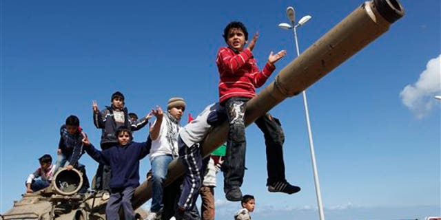 Feb. 28, 2011: Libyan boys sitting on the cannon of a destroyed army tank celebrate the freedom of Benghazi, Libya.