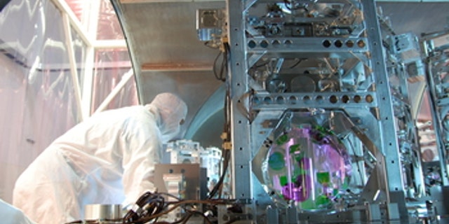 A technician works on one of LIGO's optics. At each observatory, the 2 1/2-mile long L-shaped LIGO interferometer uses laser light split into two beams that travel back and forth down the arms. The beams are used to monitor the distance between mirrors precisely positioned at the ends of the arms. According to Einstein's theory, the distance between the mirrors will change when a gravitational wave passed by the detector.