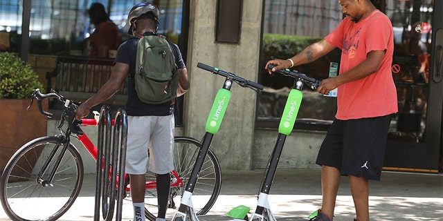 A man parks his rented dockless scooter outside of a restaurant in Atlanta. Lawsuits and cease-and-desist orders have quickly followed the arrival of California-based scooter companies.