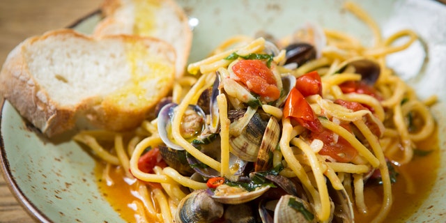 Homemade pasta with seafood and cherry tomatoes on wooden table