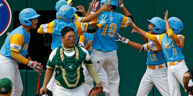 Mana Lau Kong (19) celebrates with his teammates after hitting a home run in the bottom of the first inning of Sunday's Little League World Series Championship game.