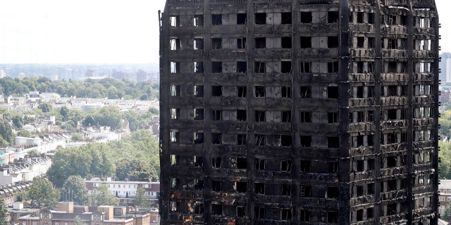 Firemen, left, inspect the scorched facade of the Grenfell Tower in London, Thursday, June 15, 2017, after a massive fire raced through the 24-storey high-rise apartment building in west London early Wednesday. Firefighters are beginning the task of combing through the devastated apartment tower, checking integrity of the structure and searching to find victims.(AP Photo/Frank Augstein)