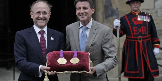 July 2, 2012: Sebastian Coe, chairman of the London 2012 Organizing Committee, and Jan du Plessis, left, Rio Tinto mining company chairman, pose for the photographers holding a gold medal of the Games, during a photo op at the Tower of London, in London.