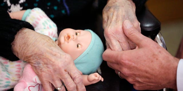 FILE - In this April 14, 2016, file photo, a son holds his mother's hand at her nursing home in Adrian, Mich. Long-term care grew more expensive again in 2016, with the median annual bill for a private nursing home room edging closer to $100,000, according to a survey released Tuesday, May 10, 2016, from Genworth Financial. (AP Photo/Carlos Osorio, File)