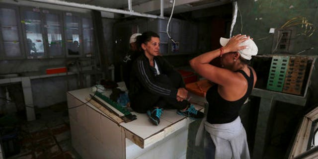 Butcher shop owner Liliana Altuna, left, speaks with an employee inside her shop that was looted the night before, at El Valle neighborhood in Caracas, Venezuela, Friday, April 21, 2017.