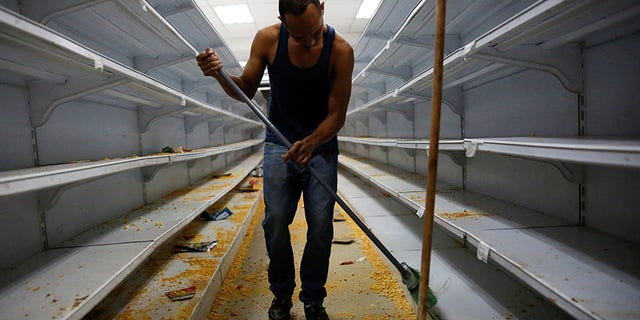 A worker cleans the shelves in a supermarket after it was looted in Caracas, Venezuela April 21, 2017.