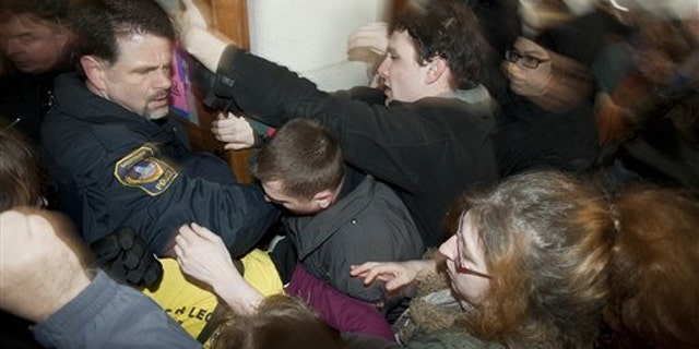 Police try to secure a door during a protest at the Wisconsin state Capitol March 10 in Madison.
