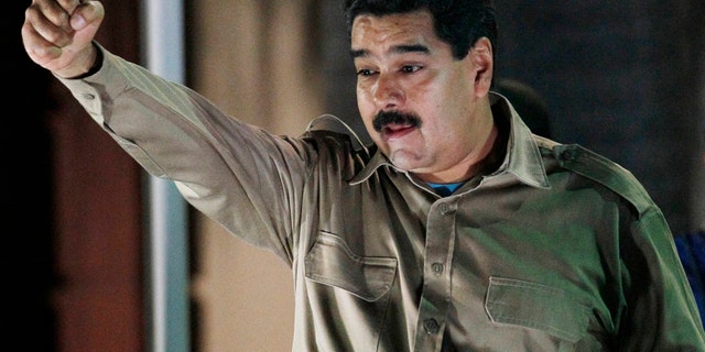 El presidente de Venezuela Nicolás Maduro sostiene los documentos que le otorgan facultades para gobernar por decreto mientras saluda a simpatizantes en el palacio presidencial de Miraflores, en Caracas, Venezuela, el martes 19 de noviembre de 2013. Maduro promulgó dos dÃas después las dos primeras leyes. (AP Foto/Ariana Cubillos)