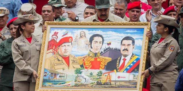 President Maduro holds a painting depicting late President Chavez, Venezuelan liberator Simon Bolivar and himself during march to commemorate 7th anniversary of the Bolivarian Militia in Caracas, Apr. 17, 2017.