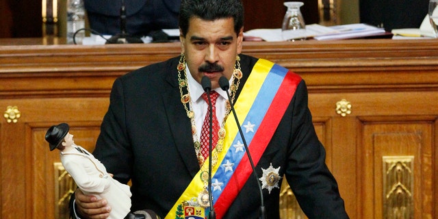 Maduro holds a statue of the beloved physician folk-saint Dr. Jose Gregorio Hernandez as he delivers a speech at the National Assembly in Caracas, Venezuela, Tuesday, Oct. 8, 2013.