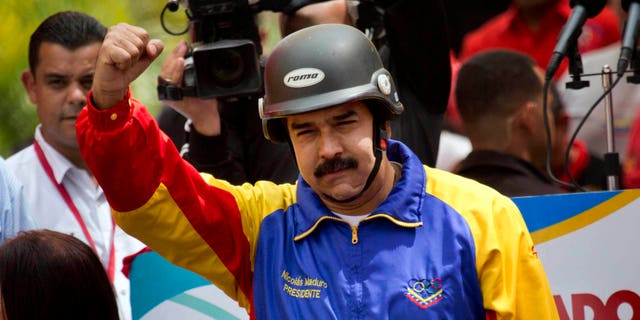 A helmet wearing Venezuelan President Nicolas Maduro cheers motorcyclists during a rally in support of his government in Caracas, Venezuela, Monday, Feb. 24, 2014. Since Feb. 12, opponents of President Nicolas Maduro have been staging countrywide protests that the government says have resulted in scores of deaths and more than more than a hundred injured. The demonstrators blame Maduro's administration for the country's high crime rate and economic troubles. (AP Photo/Rodrigo Abd)