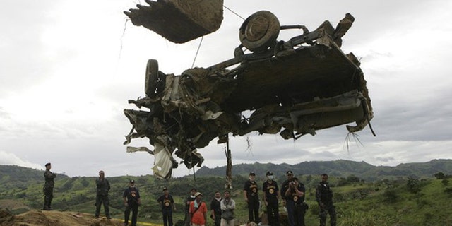 A backhoe lifts the wreckage of a local television network's vehicle that was unearthed from a shallow grave at the site of a massacre of a political clan that included several journalists in the outskirts of Ampatuan, Maguindanao in southern Philippines in this November 25, 2009 file photo. The 2009 massacre of 57 people, including 31 journalists, in the southern province of Maguindanao was horrific even by the standards of the Philippines, whose restive south is riven by political and insurgent violence.