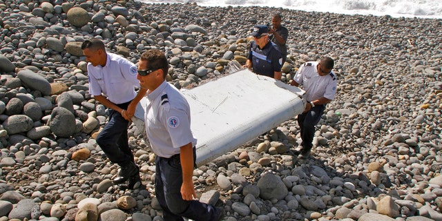 July 29, 2015: French police officers carry a piece of debris from a plane known as a flaperon in Saint-Andre, Reunion Island. The barnacle-encrusted part was the first trace found of Malaysia Airlines Flight 370, which disappeared two years ago.