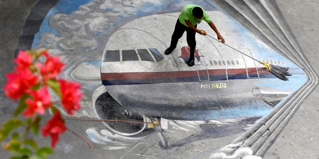 April 8, 2014: A school utility worker mops a mural depicting the missing Malaysia Airlines Flight 370 at the Benigno "Ninoy" Aquino High School campus at Makati city east of Manila, Philippines.