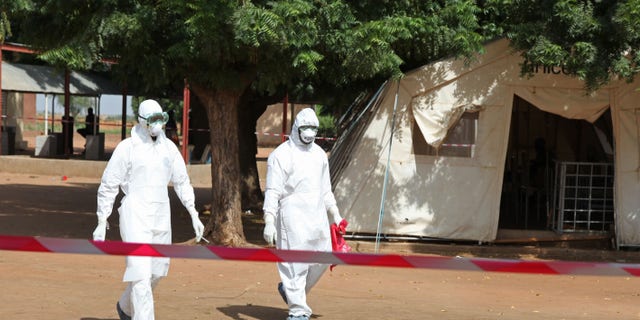 Oct. 25, 2014: Health workers walk towards an area used for Ebola quarantine after they worked with diseased Fanta Kone at a Ebola virus center in Kayes, Mali