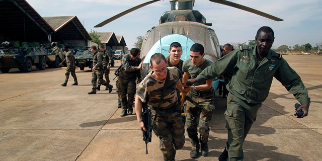 Jan. 15. 2013: Malian soldiers helped by French troops, move a broken helicopter out a hangar to make room for more incoming troops  at Bamako's airport.