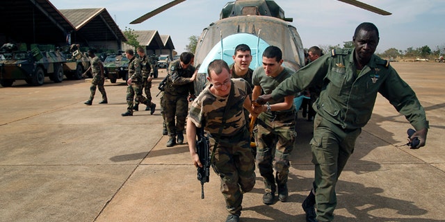 Jan. 15. 2013: Malian soldiers helped by French troops, move a broken helicopter out a hangar to make room for more incoming troops at Bamako's airport.