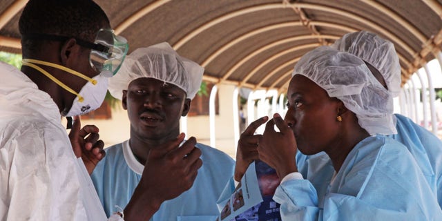 Oct. 25, 2014: A health worker, right, briefs another, left, on the use of their Ebola security gear before working with diseased Fanta Kone at a Ebola virus center in Kayes, Mali