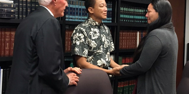 Keith Lee, center, a lawyer representing the Waianae Coast Health Center, holds hands with Rachel Marrero as her attorney Richard Fried looks on at a news conference in Honolulu, Wednesday, Sept. 14, 2016. The federal government is settling her malpractice lawsuit for $4.2 million after her husband went to the Waianae Coast Comprehensive Health Center with a sore throat and ended up dead. (AP Photo/Jennifer Sinco)