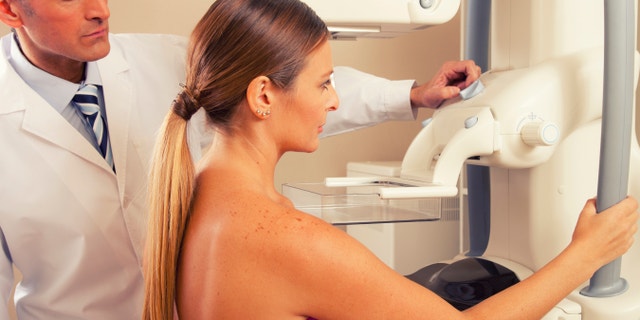 doctor checking mammography machine scan with patient woman in 40s.