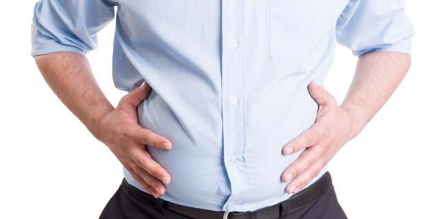 Hands grabbing bloated abdomen. Digestion problem or indigestion, medical concept.