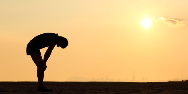 Silhouette of an exhausted sportsman at sunset with the horizon in the background