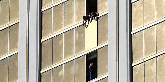 Workers board up a broken window at the Mandalay Bay hotel where Stephen Paddock shot out of.