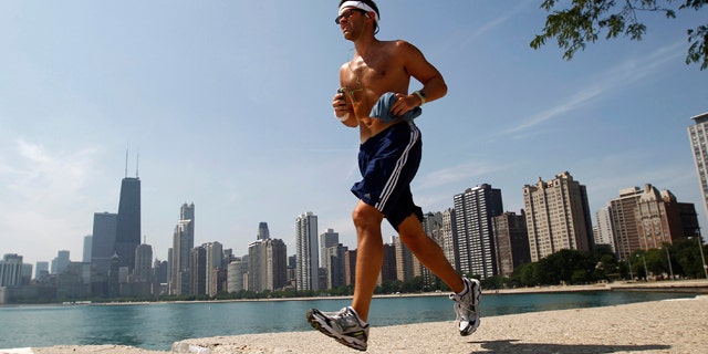 A man runs along the water near North Avenue Beach in Chicago July 20, 2011. The heat index is expected to exceed 110 degrees Fahrenheit or 43 degrees Celsius. REUTERS/Jim Young (UNITED STATES - Tags: ENVIRONMENT)