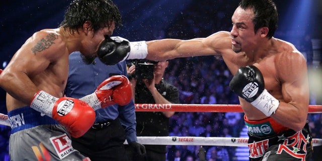 Dec. 8, 2012: Juan Manuel Marquez, right, lands a right to the head of Manny Pacquiao during their WBO world welterweight fight in Las Vegas. Marquez won by a knockout. Pacquiao reportedly wants his next bout -- a fifth fight against Marquez -- to be held far away from Sin City and the United States’ 39.6 federal tax rate. (AP)