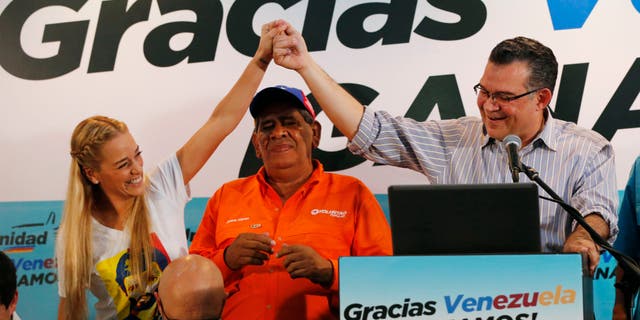 Lilian Tintori, esposa del encarcelado líder opositor Leopoldo López, izquierda, sostiene la mano del reelecto legislador Enrique Márquez, del estado Zulia, durante una rueda de prensa en Caracas, Venezuela, el lunes 7 de diciembre de 2015. La oposición venezolana ganó el control de la Asamblea Nacional en las elecciones del domingo 6 de diciembre. (AP Photo/Ariana Cubillos)
