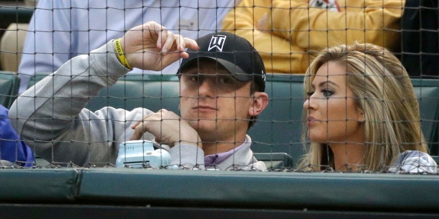 April 14, 2015: Johnny Manziel, left, sits with Colleen Crowley during a baseball game between the Los Angeles Angels and the Texas Rangers in Arlington, Texas. Dallas police announced Friday they were launching a criminal investigation into a domestic violence assault complaint filed against Manziel, who was involved in an altercation last weekend during which he allegedly struck Crowley several times. (AP Photo/LM Otero)