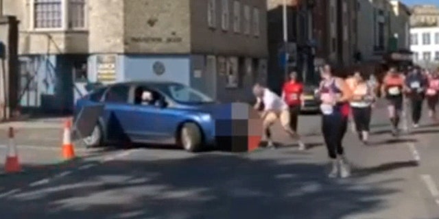 The moment when a woman tried to drive into the route of the Plymouth half marathon - while the race was underway. See SWNS story SWRACE; One of Devon's most successful athletes has slammed a woman who drove her car on the route of race in Plymouth this morning. Hundreds of participants were left aghast as the woman knocked over road closure cones and attempted to cross the path of runners taking part in the Britain's Ocean City Half Marathon today. The incident, which was captured on film by eyewitness Rob Bricknell, left many people in shock - one of whom was Plymouth's GB Sprint Hurdler David King. He took to Twitter to express his disbelief. He described it as "disgusting behaviour" and said "you need to watch the video to believe it".