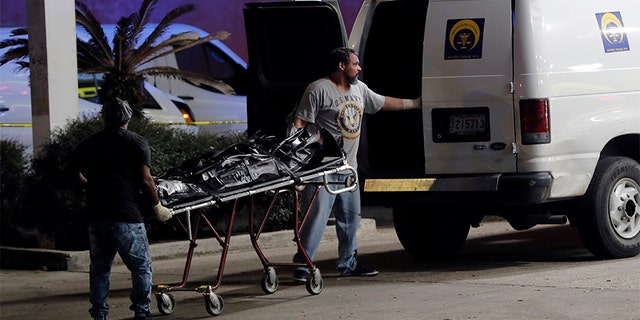 Police move a body into a coroner van at the scene of a Mardi Gras Day shooting that left at least one dead and others injured in the Lower 9th.