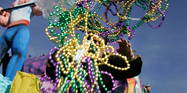 A parade rider throws out handfuls of beads during a Mardi Gras parade.