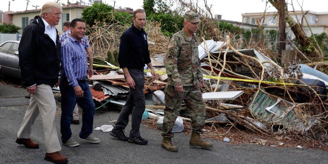 President Donald Trump walks with FEMA administrator Brock Long, second from right, and Lt. Gen. Jeff Buchanan, right as he tours an area affected by Hurricane Maria in Guaynabo, Puerto Rico, Tuesday, Oct. 3, 2017.